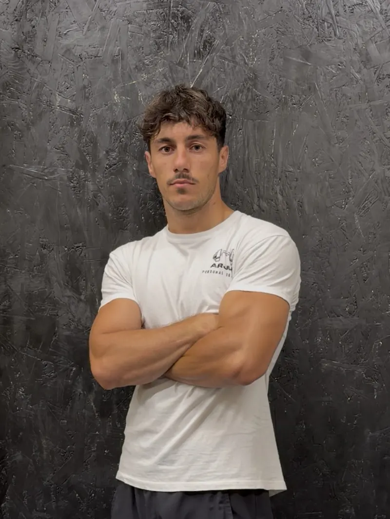 Arjus Vahaj, personal trainer a Ravenna, in maglietta bianca a braccia conserte